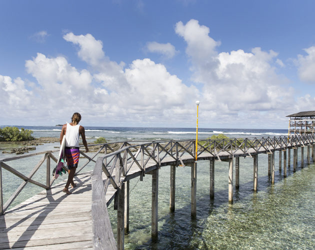 surfer walking the boardwalk to cloud 9 surf spot, Nay Palad